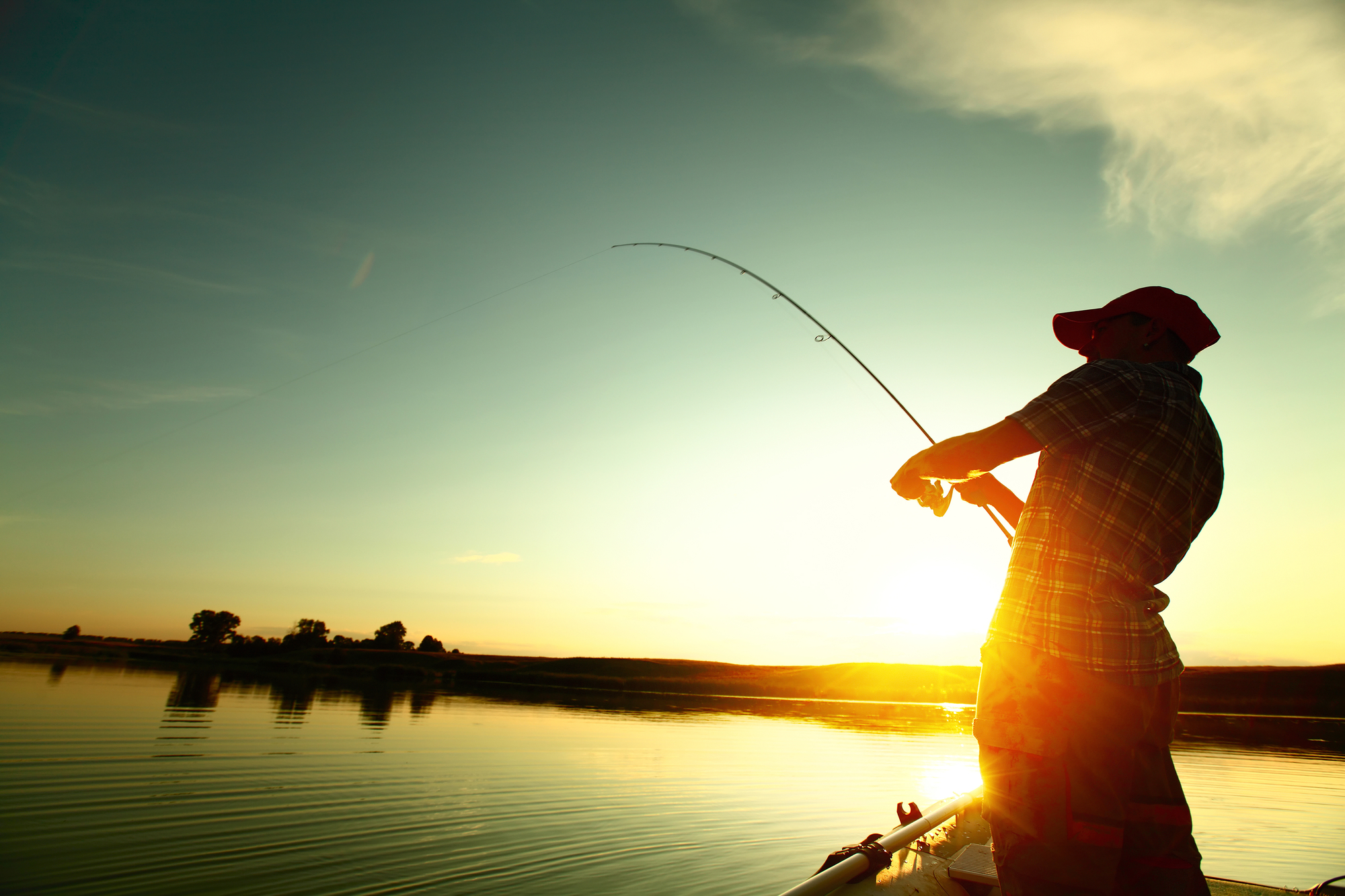 Man fishing a freshwater lake with sunset in background